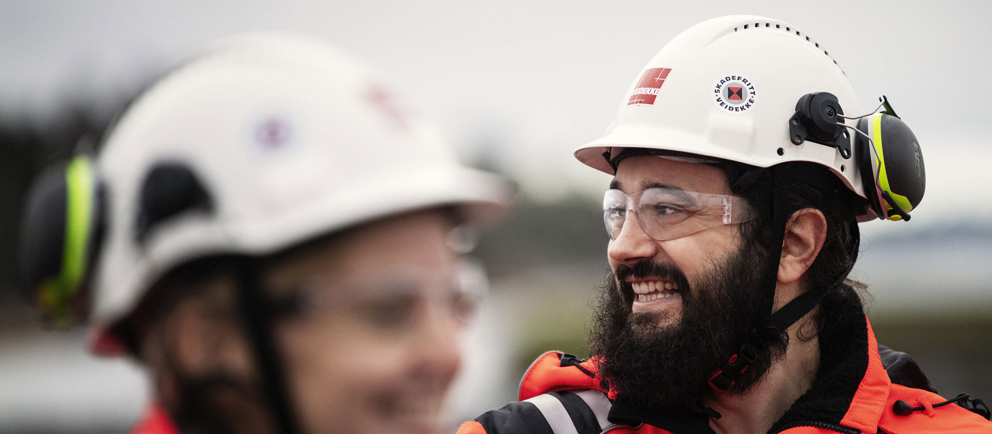 Man and woman wearing high-vis clothing and helmets. Photo.